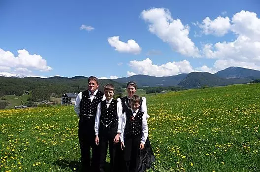 Zelená louka s kvetoucími pampeliškami u Wegmacherhofu. Rodina Gablonerových v tradicním kroji u príležitosti Floriánova birmování.
