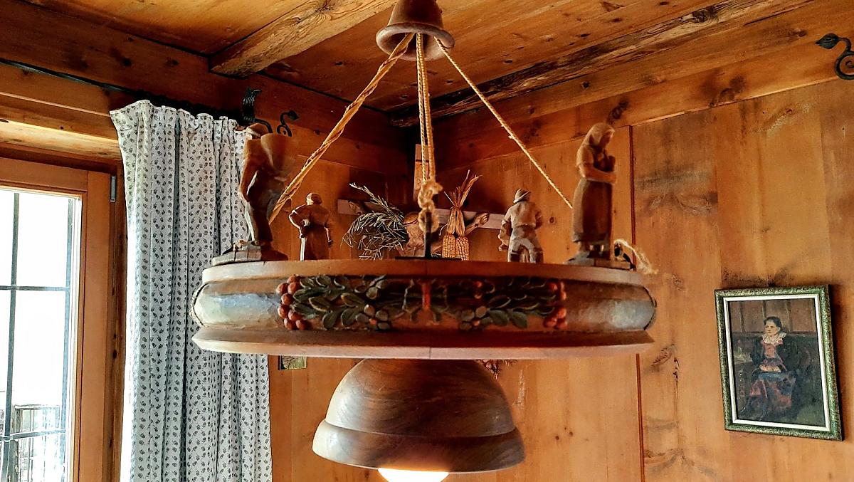 Detailní pohled na lampu ve svetnici: historický, rucne vyrezávaný unikátní kus s rustikálními drevenými figurkami