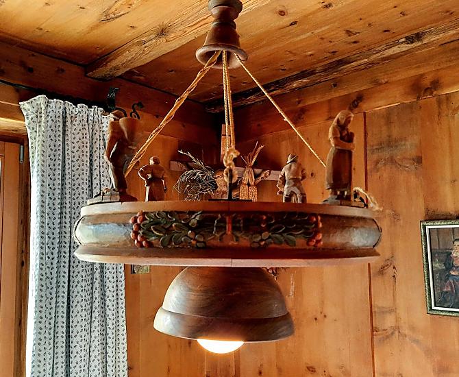 Detailní pohled na lampu ve svetnici: historický, rucne vyrezávaný unikátní kus s rustikálními drevenými figurkami