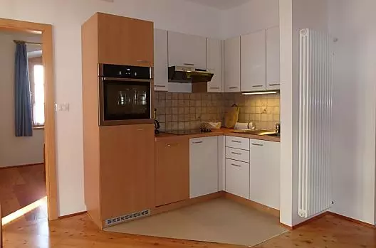 Kuchynský kout v obývacím pokoji rekreacního apartmánu Abendsonne je vybaven myckou nádobí a troubou.