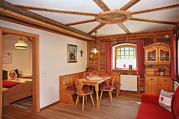 Wohnzimmer mit Holzboden und Innenverkleidung aus veredeltem Altholz, Möbel aus Fichte-Massivholz und ausziehbarer Couch.