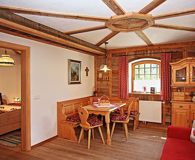 Wohnzimmer mit Holzboden und Innenverkleidung aus veredeltem Altholz, Möbel aus Fichte-Massivholz und ausziehbarer Couch.