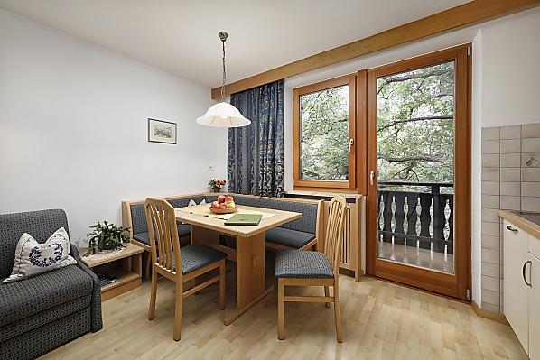 Der geräumige Wohnraum verfügt über eine gemütliche Sitzecke, eine Doppelbettcouch und einen eigenen Balkon zum Nussbaum.