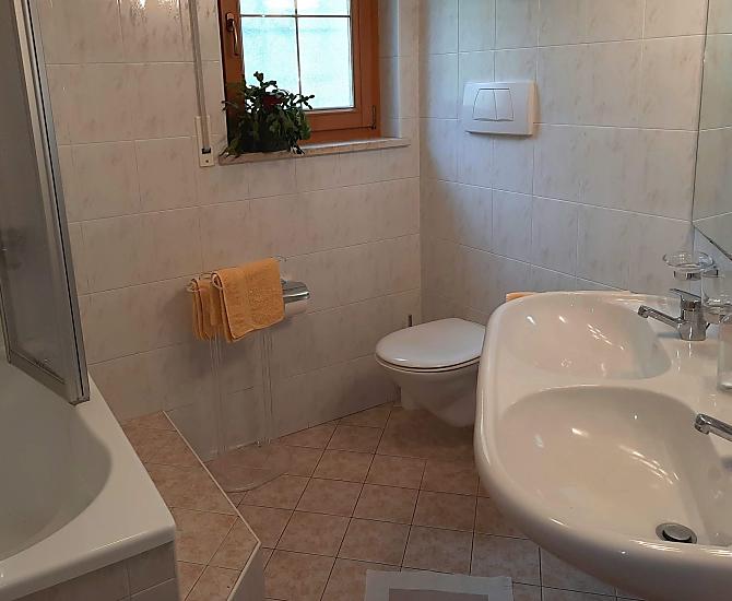 Bad mit Sitzbadewanne/Dusche, WC, Doppelwaschbecken und Handtuchtrockner