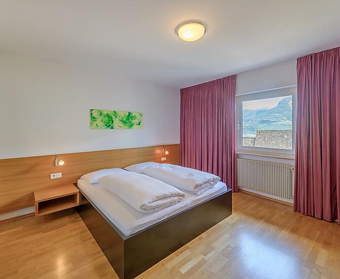 Geräumiges Doppelzimmer mit dreiteiligem Schrank, Holzboden, Bettenlänge 200 cm, Safe, direktem Zugang zum Badezimmer und Blick ins Tal.